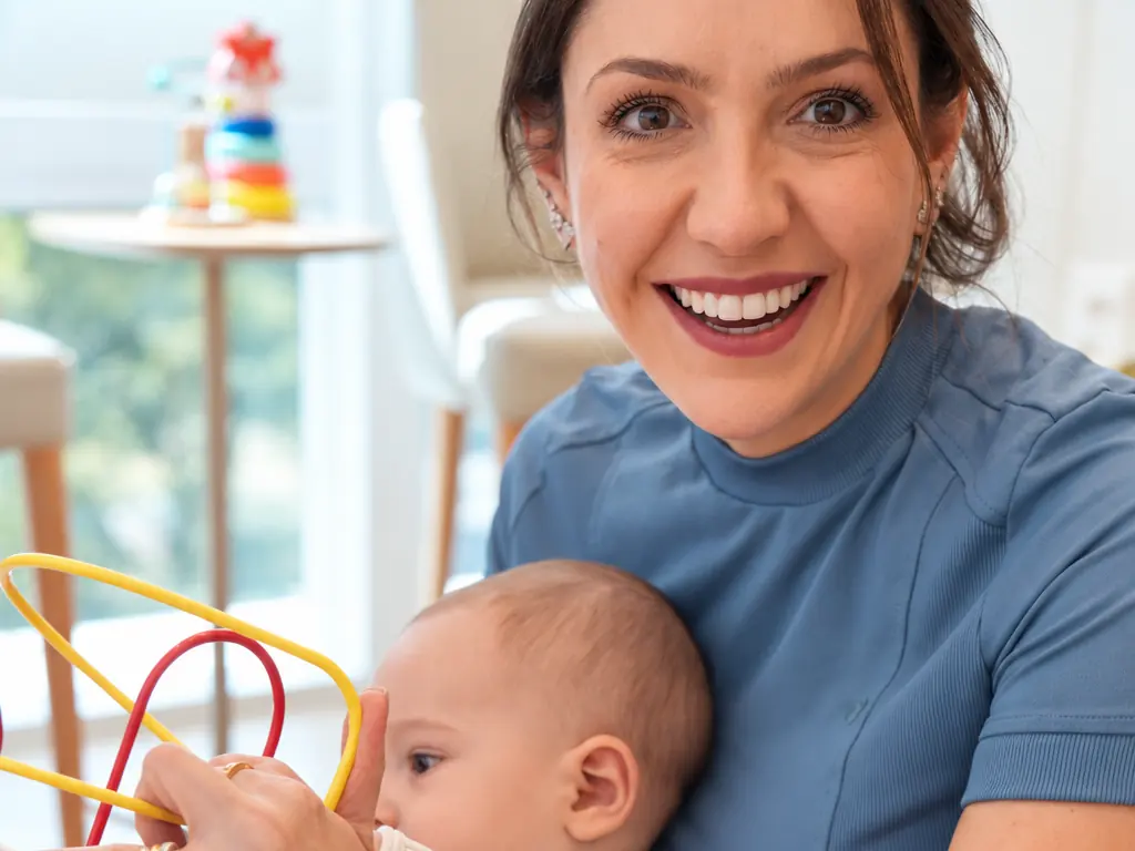 Bruna Cury sorrindo, com um bebê no colo, no consultório